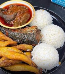 a plate with rice and meat and a bowl of sauce at E-Luxe Suites Hotel in Abuja
