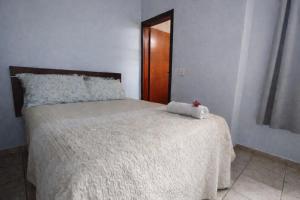 a bedroom with a bed with a white comforter at Quarto Divas na Sakura House in Indaiatuba