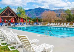 a pool with white chairs and a log cabin at Little Pine Lodge a Smokies Hideaway - 1 mi to GSMNP - King Suite & Loft, Fireplace, Hot Tub & BEARS! in Sevierville