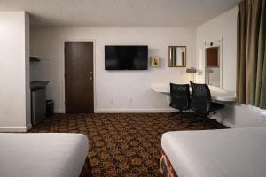 a hotel room with two beds and a flat screen tv at Granada Hotel Santa Clara in Santa Clara