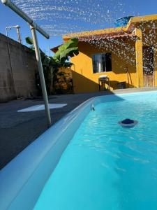 a pool with blue water in front of a house at CasadaKassia in Itapemirim +13 photos