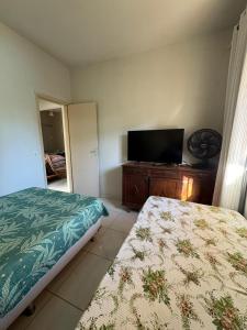 a bedroom with a bed and a flat screen tv at CasadaKassia in Itapemirim