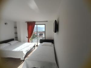 a bedroom with two beds and a window at SANTA HELENA HOSPEDERIA in Tibasosa