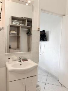 a white bathroom with a sink and a shower at Bungalow Pamatai Sky in Faaa
