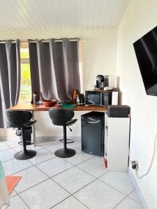 a kitchen with a table and chairs and a television at Bungalow Pamatai Sky in Faaa