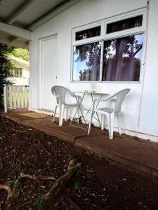 a white table and chairs on the porch of a house at Bungalow Pamatai Sky in Faaa +1 photo