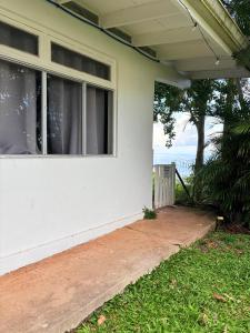 a white house with a window and a sidewalk at Bungalow Pamatai Sky in Faaa