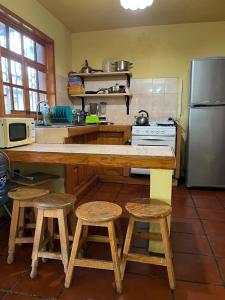 a kitchen with a counter with stools and a refrigerator at Casa del Bosque in Mazamitla
