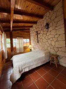 a bedroom with a bed in a stone wall at Casa del Bosque in Mazamitla
