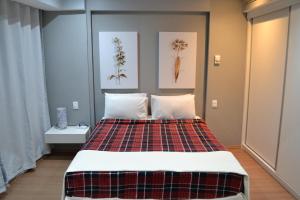 a bedroom with a bed with a plaid blanket at Airport Gru Flats in Guarulhos +30 photos