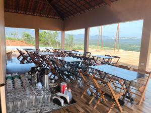 a group of tables and chairs in a room with windows at Pousada Mirante Das Serras Ibicoara-BA in Ibicoara