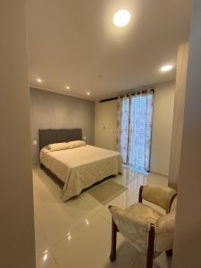 a bedroom with a bed and a chair and a window at Residencia Pura Vida in Capiatá