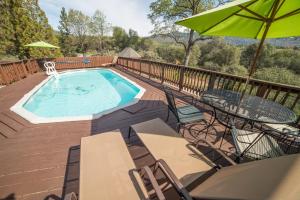 a pool on a deck with chairs and an umbrella at Nature's Inn Bed and Breakfast in Ahwahnee