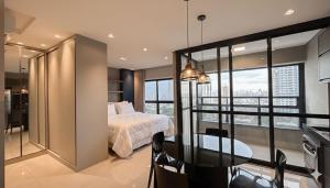 a bedroom with a bed and a table and some windows at Lindo Studio Com Vista para Cidade in Campo Grande +8 photos
