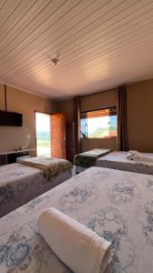 a room with three beds and two windows at Pousada Mirante Das Serras Ibicoara-BA in Ibicoara