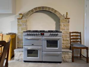 a kitchen with an oven with a stone wall at The Mill Cottage in Ault Hucknall