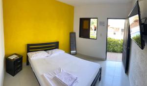 a bedroom with a bed with a yellow wall at La Masia Hostal in Taganga