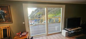a living room with a large window with a sliding door at Hardanger Fjordblikk in Syreflot +12 photos