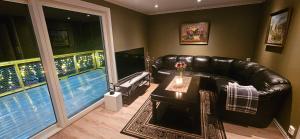 a living room with a leather couch and two large windows at Hardanger Fjordblikk in Syreflot
