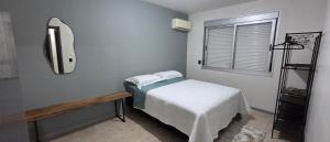 a small bedroom with a bed and a mirror at Apto térreo aconchego e localização central in Santa Rosa