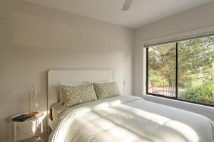 a white bedroom with a bed and a large window at An Unforgettable View in Dixons Creek
