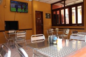 uma sala de jantar com mesas e cadeiras e uma televisão em Hotel Pasadena II em San Salvador