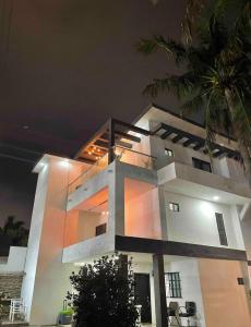 a large white house at night with a palm tree at Acogedora recámara, con balcón y entrada independiente in Tampico