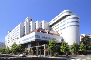 a large white building with a car parked in front of it at Jasmac Plaza Hotel in Sapporo