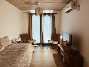 a bedroom with a bed and two chairs and a television at Maju in Neuquén