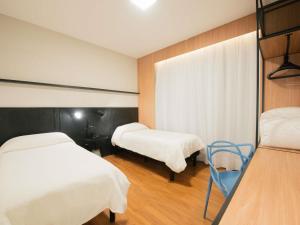 a hospital room with two beds and a chair at ibis Curitiba Shopping in Curitiba