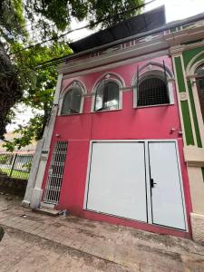 a red house with two white garage doors at Hostel Cünhatã in Belém