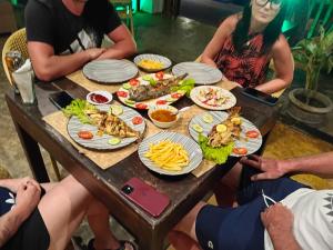 a group of people sitting around a table with food at Harmony Beach Hotel - Tangalle in Tangalle