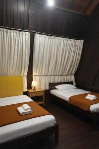 two beds in a room with white curtains at Villa Argapuri Hills in Ciwidey