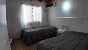 two beds in a small room with a window at Departamento Escobar in Belén de Escobar