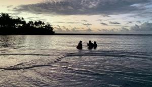 three people standing in the water in the ocean at Bokanbotin Island Resort in Majuro +3 photos