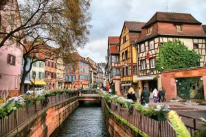 a group of people walking along a river in a city at Maison avec terrasse Colmar Centre-Cottage garden terrace Center Old Town Colmar in Colmar