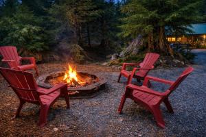 three red chairs sitting around a fire pit at New Tiny Home Steps Away From Mt. Rainier in Ashford +1 photo