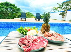 a table topped with plates of food next to a pool at ulu Okinawa Resort in Motobu