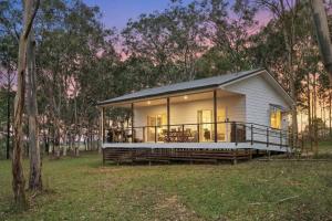 a small white house with a large deck at 27 Rows on Hermitage in Pokolbin