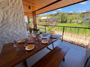 a wooden table with plates and glasses on a balcony at Diamantino Residence - apt 07 CalmariaMucuge in Mucugê