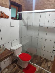 a bathroom with a toilet with a red seat at Chalés Beira Rio in Santo Antônio do Pinhal