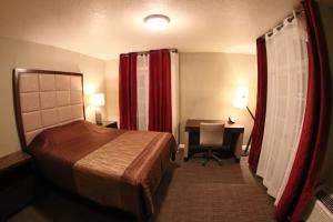 a hotel room with a bed and a desk with a computer at Santa Cruz Inn in Riverside