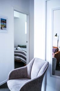 a chair in a room with a bedroom at Top Floor - Secure Parking - Great Location - Quiet - City Ciew in Wellington