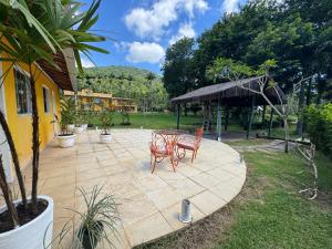 a patio with two chairs and a table in a yard at Sítio Mais Lindo do Mundo in Ilha de Guaratiba
