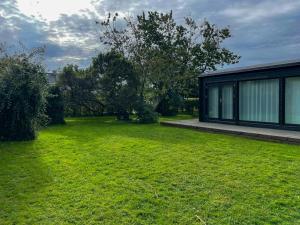 a green yard with a house and a building at Stylish House Between Beach And Forest In Tisvilde in Tisvilde