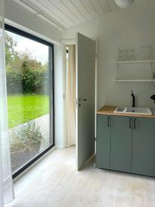 a kitchen with a sink and a large window at Stylish House Between Beach And Forest In Tisvilde in Tisvilde