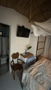 a bedroom with a bed and a tv and a chair at Desapegue & Viva Bed and Bikes in Ilhéus