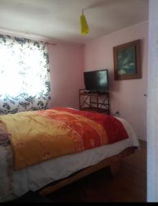 a bedroom with a bed and a television and a window at Cabaña La Isla in Isla Negra