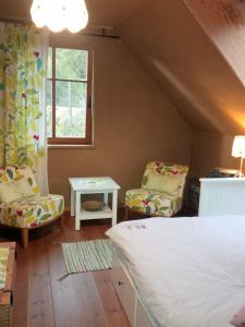 a bedroom with a bed and two chairs and a window at Ferienhof Idyll am kleinen Fließ in Burg