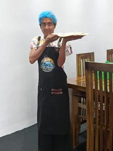 a woman in an apron holding a pizza at Nil Manel Tourist in Anuradhapura